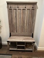 Front view of the wooden hall tree bench showing the full unit with hooks and storage cubbies underneath the seat.