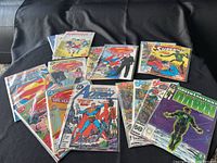 Photo showing multiple DC comic books including Superman The Man of Steel, Action Comics with Superman and the Teen Titans, Green Lantern issue 1, and Robotech comics.