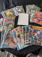 Full view of all comics arranged on black surface with a white embossed cover comic in center.