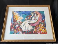 Framed art print showing colorful abstract figures and village scene under a moonlit sky, signed and numbered.