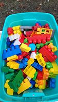 Blue plastic bin filled with assorted Mega Bloks showing various colors and sizes piled inside.