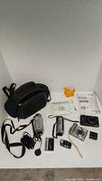 Various cameras and digital camcorders with accessories and carrying case.