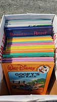 Photo showing box filled with Disney children’s books, colorful spines visible including 'Goofy’s Big Race' on top.