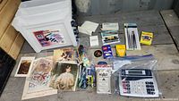 Contents of file box including office supplies and collectible prints spread on surface