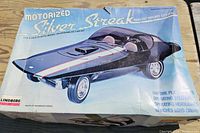 Box top of Lindberg Motorized Silver Streak 1:12 scale plastic model kit showing the assembled model car in black with red and white stripes and details about features like chrome plating, operating steering, and headlights.