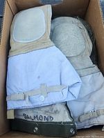 Top view of two pairs of insulated cold weather gloves showing inner and outer palms and gauntlet cuffs in a box