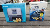 Photo showing the boxes of the two printers: Canon Selphy CP710 on left and Polaroid Portable Digital Photo Printer on right.
