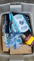 Storage bin containing boxed Mastercraft smoke alarm, plastic bags with hardware bits and other items.