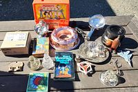 Full lot overview showing many collectible and household items including Peanuts lunch box, ashtray, decanter tops, book, glass bowls, and others