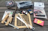 Varied items including mobile router, tire iron, collectible cards, toy car, Harley Davidson lock, axe head and music CDs laid out on wooden surface.
