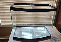 Front view of empty bow-front glass aquarium showing black trim and curved glass.