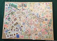 Photo showing a wide assortment of loose used Chinese postage stamps spread out, featuring diverse themes like flowers, animals, and traditional imagery.