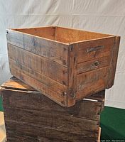 Front side view of wooden crate showing plank construction and one built-in slot handle.