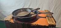 Set of two cast iron pans, 9-inch and 6-inch Lodge skillets arranged on wooden surface