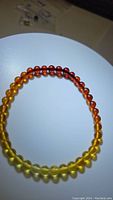 Photo of a stretchy bracelet made with round Baltic amber beads showing a color gradient from yellow to deep amber.