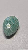 Close-up photo of a 2.14ct natural amazonite gemstone shaped like a kite with checkerboard faceted top surface showing light blue-green color and natural striations.