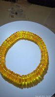 Photo of the natural AAA golden amber chunky bead stretchy bracelet coiled on a white plate, showing the translucent golden yellow beads in a close-up perspective.