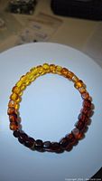 Full view of the Baltic amber bracelet showing the gradient color beads arranged in a circle on a white surface.