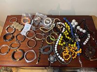 Photo showing the assortment of bracelets and necklaces laid out on a wooden surface, including a mix of bangles, stretch bracelets, and beaded necklaces.