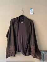 Dark brown open-front knit cardigan with shawl collar and ruffle-textured hem and cuffs