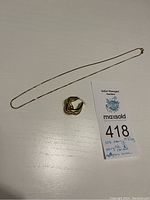 Photo of 10k gold chain and single 14k gold earring with auction lot tag showing description and weight