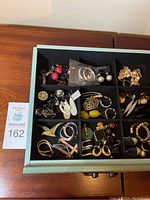 Drawer with 12 black felt compartments holding earrings and brooch