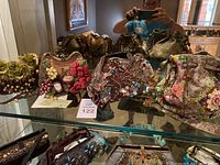 Four Mary Frances purses displayed on glass shelf