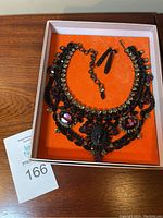 Necklace and earrings displayed in box on orange background