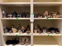 Overview of two shelves displaying a total of 14 pairs of women's shoes of various styles and colors.