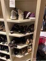 Shelves holding multiple pairs of women's shoes of different styles and colors including beige, black, gray, and purple