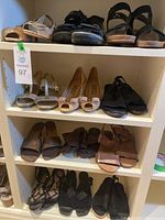 Shelf display of the 12 pairs of women's size 7 shoes showing a variety of styles including sandals, flats, and heels.