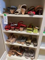 Shelving unit with 12 pairs of women's heeled sandals in various colors including red, beige, olive green, tan, and metallic gold, arranged in four rows.