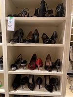 Four shelves displaying 12 pairs of women's heels and sandals in mixed styles and brands