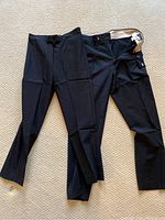 Three pairs of black pants laid flat on carpet
