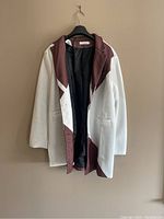 White and burgundy pinstripe patchwork coat hanging on hanger