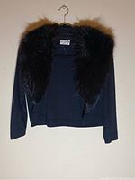 Front view of black open-front cardigan with faux fur collar on hanger