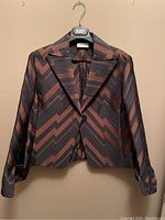 Zigzag-pattern cropped blazer on hanger against wall