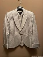 Silver brocade blazer hanging on branded hanger