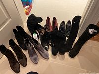 Overview of all nine pairs of boots arranged on floor showing variety of styles