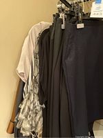 Hanging women's clothing items showing various skirts and blouses in neutral colors