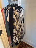 Photo showing various dresses hung on a rack with a visible floral print off-shoulder dress in front and other assorted dresses behind.
