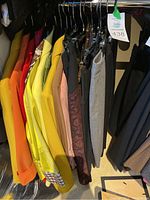 Photo of assorted colorful women's tops and skirts hung on a rack, showing variety and condition