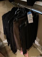Clothing items hanging on rack including skirts and tops in dark colors