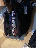 Rack of skirts and tops on hangers showing assortment of black and neutral garments