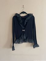 Black cardigan with satin ruffle trim on collar, hem, cuffs, and double ring front closure