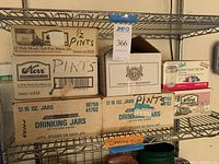 Shelving with six boxes of assorted canning jars including Kerr, Ball, and Golden Harvest brands in original packaging boxes.