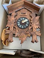 Close-up of hand-carved cuckoo clock face and wooden housing featuring leaf patterns.