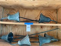 Group view of six matching tulip-shaped metal garden lights laid horizontally inside wooden shelving.