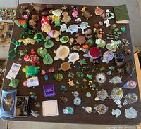 Top-down photo showing a large assortment of turtle figurines on a table, variety of materials, colors, and sizes evident