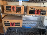 Three Kenwood component boxes labeled KT-7300 AM-FM stereo tuner, KA-620 stereo cassette deck and KA-7100 stereo integrated amplifier on wire shelf